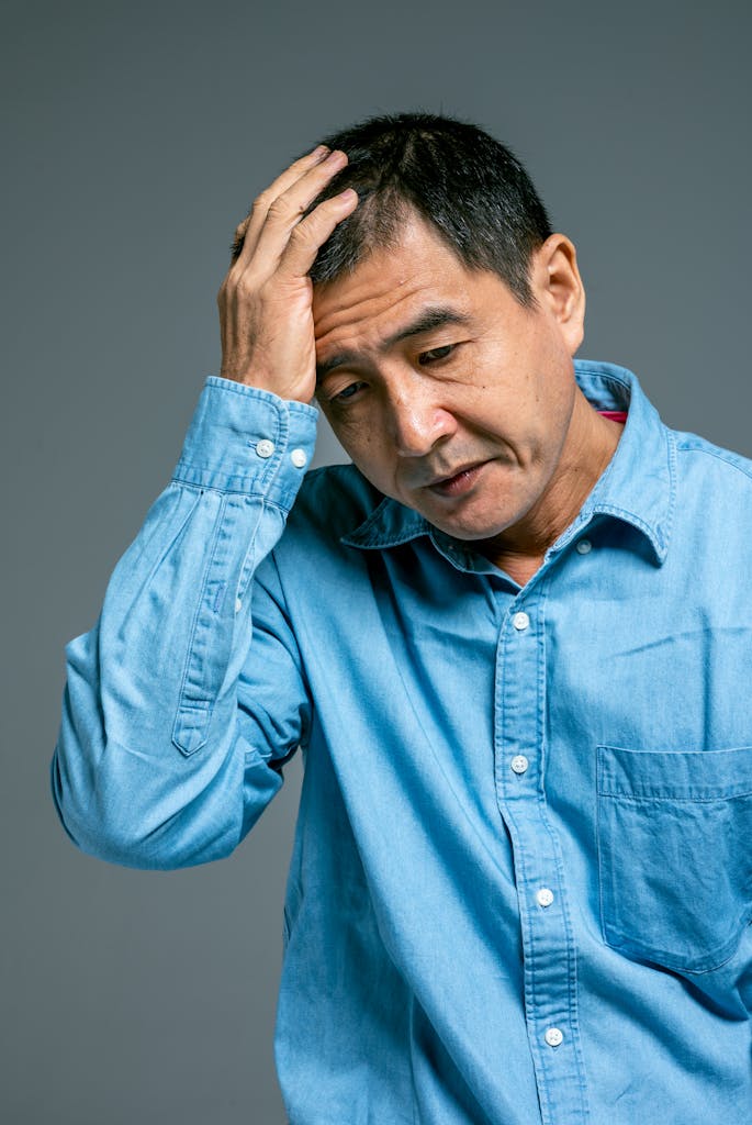 Worried adult man in blue denim shirt. Mental health and stress concept.